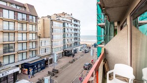 Ein Hochhaus mit mehreren Balkonen mit Blick auf eine Straße und einen Strand.