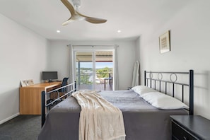 A bedroom with a bed, a desk, a chair, a ceiling fan, and a balcony door. - Green Island View Manyana (Manyana)