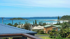 A coastal view with a house, a beach, and a clear sky.