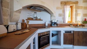 Une cuisine avec des murs en pierre, un four encastré, une machine à café et un grille-pain.