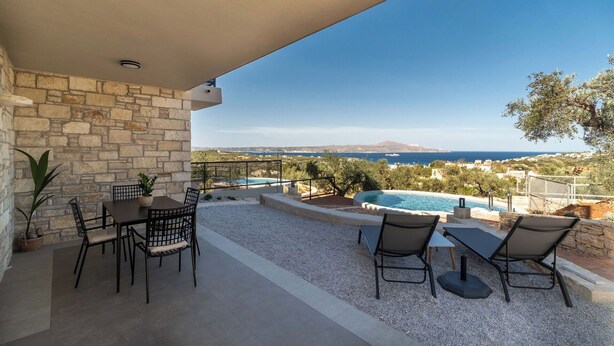 Une terrasse avec des murs en pierre, une piscine et des sièges d’extérieur.