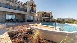 A modern villa with a pool, stone walls, outdoor seating, and a view of the mountains. - Villa Seiri – Vacation villa in Crete (Gavalochori)