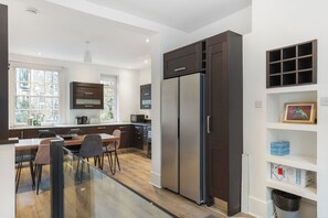 Eine moderne Küche mit einem großen Kühlschrank, Holzschränken und einem Essbereich mit Stühlen.