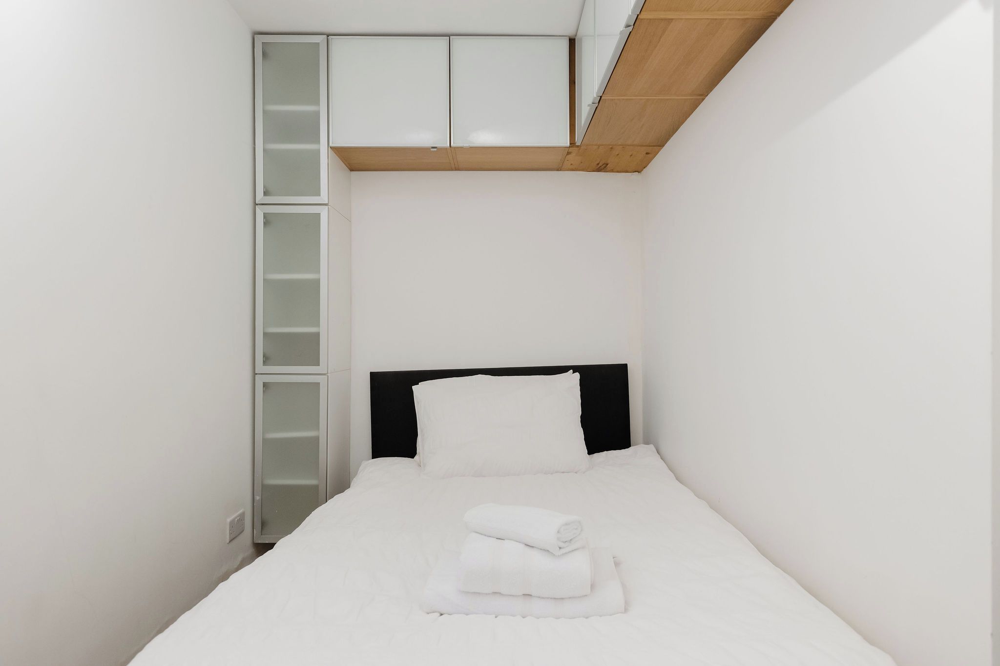 Ein Schlafzimmer mit einem Bett, einem schwarzen Kopfteil, einem weißen Matratze und einem weißen Handtuch.