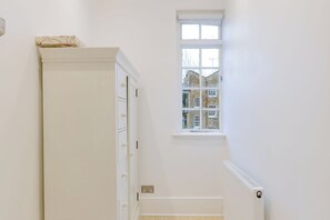 Ein heller Innenraum mit Fenster, Heizkörper und einer Tür mit Schrank.