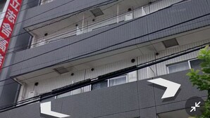 Monikerroksinen rakennus, jossa on punainen, pystysuunnassa oleva kyltti, useita parvekkeita ja ruudukkomainen julkisivu.