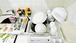 Keittiössä on valkoiset laatat, pesuallas sekä erilaisia keittiövälineitä ja astioita, jotka on järjestetty selkeisiin säilytysastioihin.