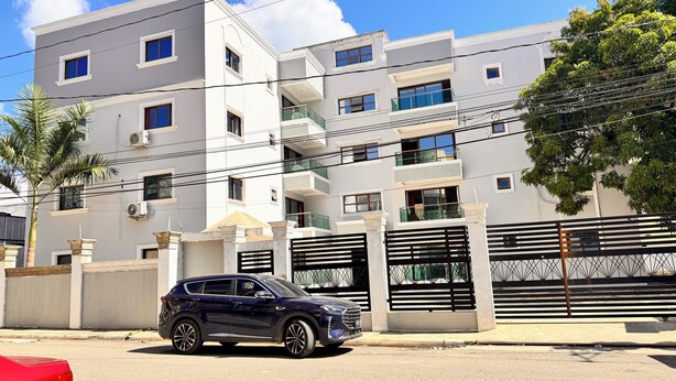 A multi-story residential building with balconies, a gated entrance, and a parked car. - Santiago Amazing 4bedrooms Apt for Group, Spectacular Wifi, Close to all fun (Santiago de los Caballeros)