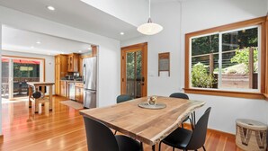 Una cocina moderna con armarios de madera, una mesa de comedor con sillas y un ventanal con vistas al verdor.