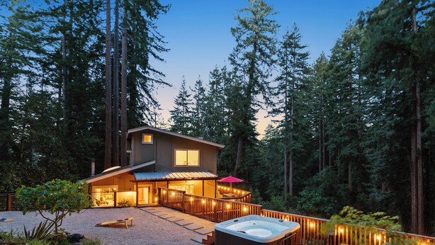 Una casa moderna con jacuzzi, terraza y un entorno boscoso.