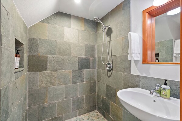 A bathroom with a shower, a sink, and a mirror.