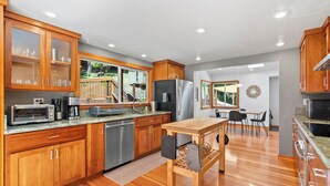 Una cocina moderna con armarios de madera, electrodomésticos de acero inoxidable y una mesa de comedor de madera.