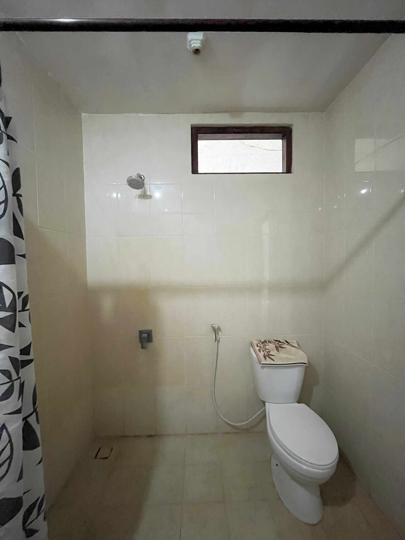Un baño pequeño con inodoro, ducha y ventana.