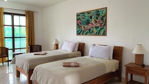 A hotel room with two beds, a window with curtains, a painting on the wall, and a small table with a lamp. - Hotel Patma Bira (Bira)