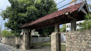 A stone wall with a sign for "Patma Bira Hotel" and a covered area with a red roof. - Hotel Patma Bira (Bira)