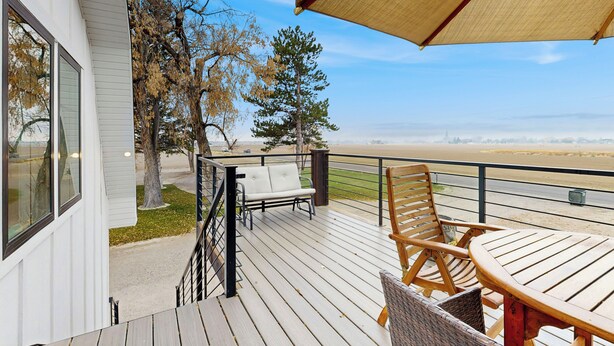 Een terras met tafel en stoelen, met uitzicht op een strand.