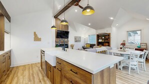 Een moderne keuken met houten kastjes, een wit aanrecht en hanglampen.