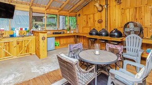 A rustic wooden cabin with a kitchen area, dining table, and chairs.