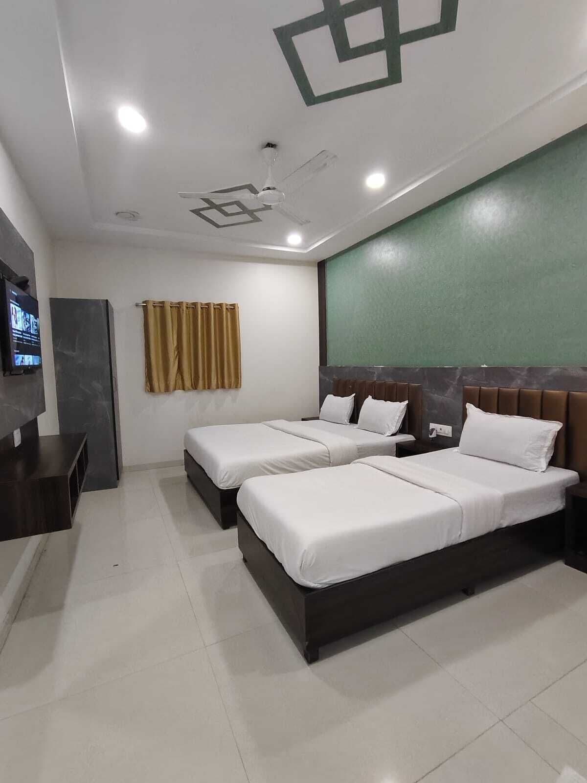 A hotel room with two beds, a TV, and a green accent wall.