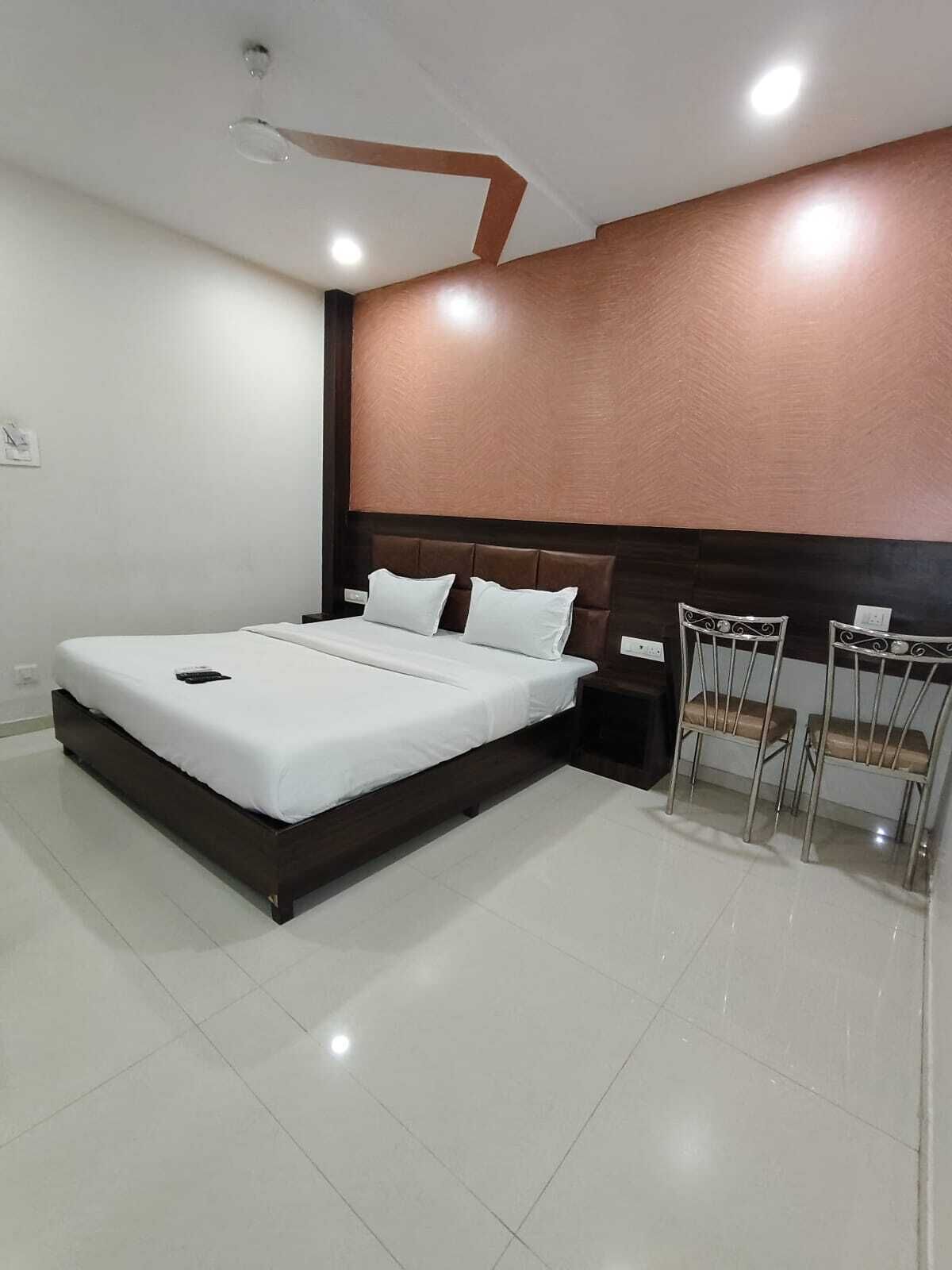 Una habitación de hotel moderna con una cama grande, un cabecero de madera y una pequeña mesa con dos sillas.