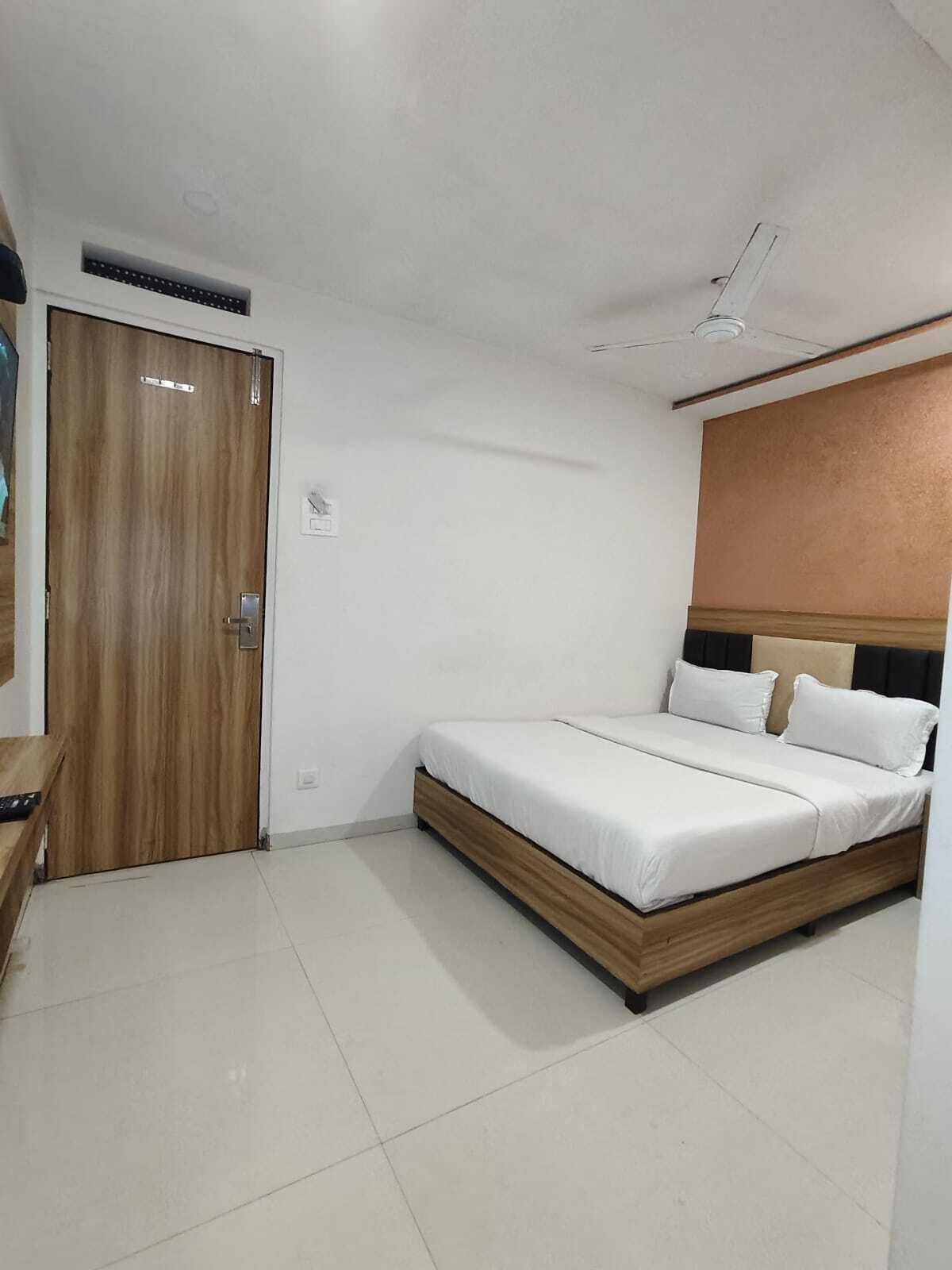 A bedroom with a wooden bed, a ceiling fan, and a door.