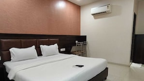 A modern hotel room with a large bed, a ceiling fan, and an air conditioning unit. - HOTEL BKC NX Rooms (Mumbai)