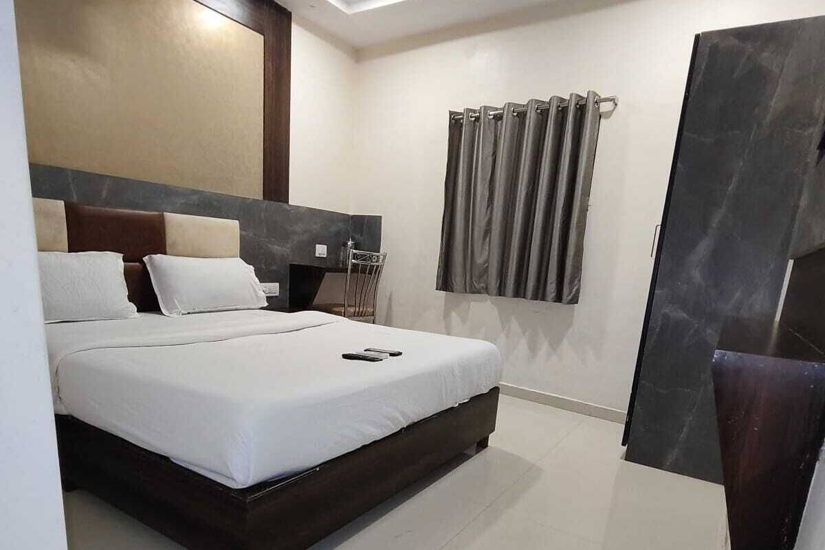 A modern hotel room with a large bed, a desk, and a ceiling fan.