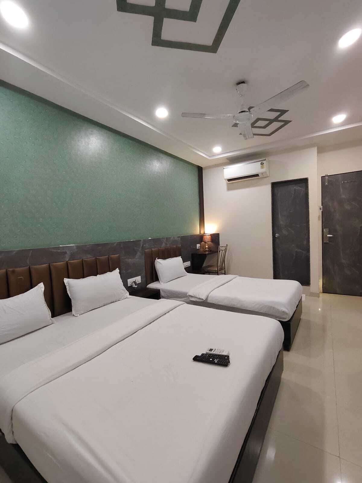 A hotel room with two beds, a ceiling fan, an air conditioning unit, and a door.