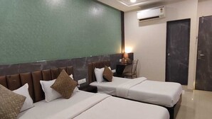 A hotel room with two beds, a ceiling fan, an air conditioning unit, and a door. - HOTEL BKC NX Rooms (Mumbai)