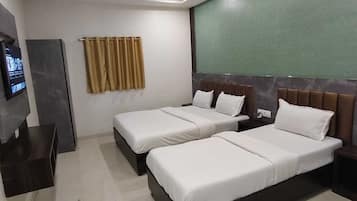 A hotel room with two beds, a TV, a wardrobe, and a ceiling fan.