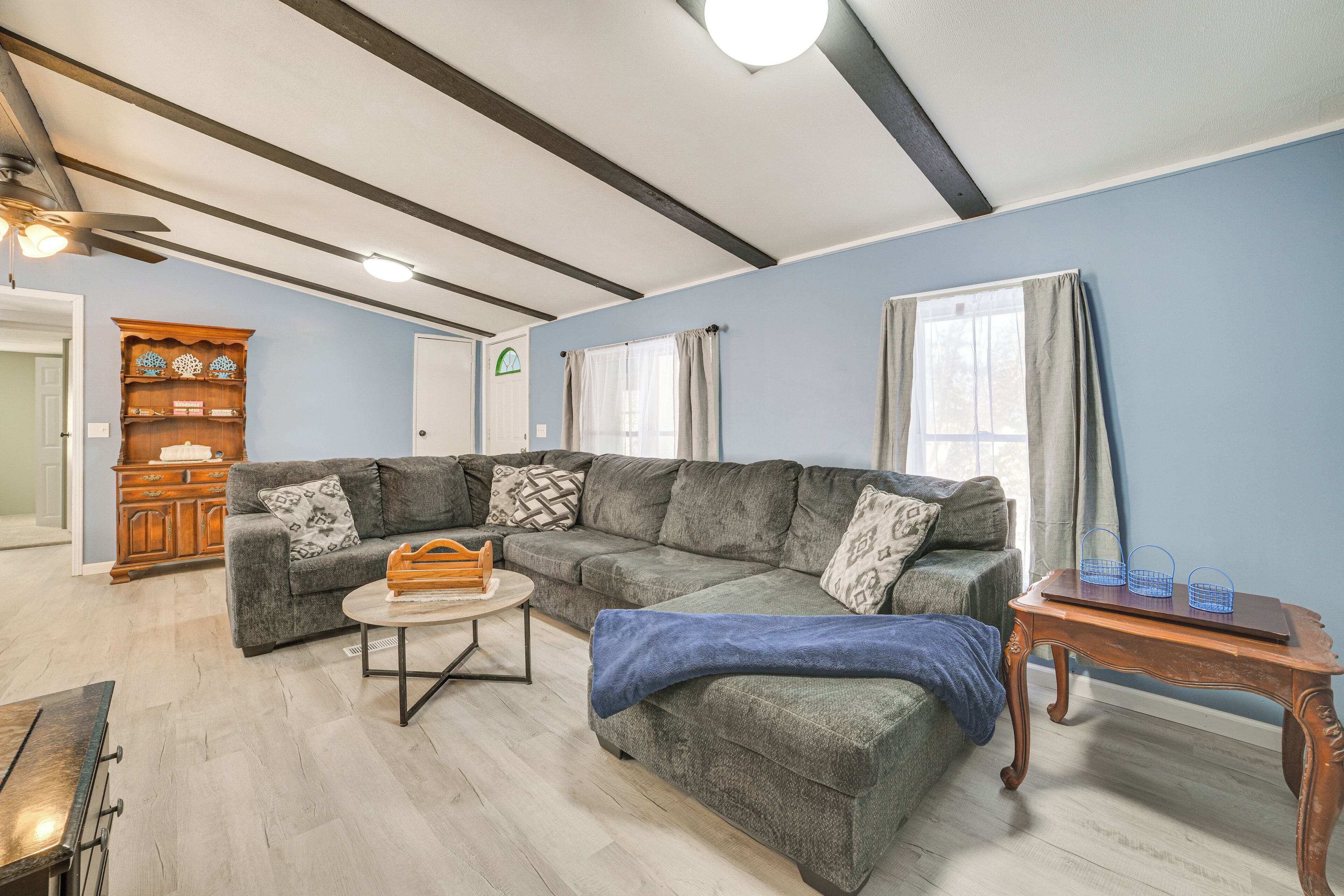 A living room with a sectional sofa, a coffee table, a wooden side table, and a ceiling fan.