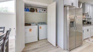 A compact kitchen with a stainless steel refrigerator, built-in washer and dryer, and white cabinetry. - Home 2 Mi to Hermann Park, Zoo & Museum District! (Houston)