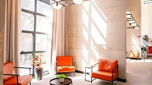 A modern interior with large windows, orange seating, and a central table with a plant. - UENO 906 (Sao Paulo)