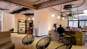 A modern interior with a bar area, seating, and a person working at the bar. - UENO 906 (Sao Paulo)