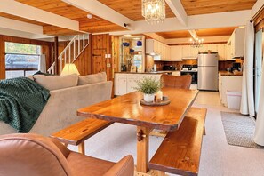 Une cuisine moderne avec des meubles en bois, un réfrigérateur en acier inoxydable et un coin repas comprenant une table et des bancs en bois.