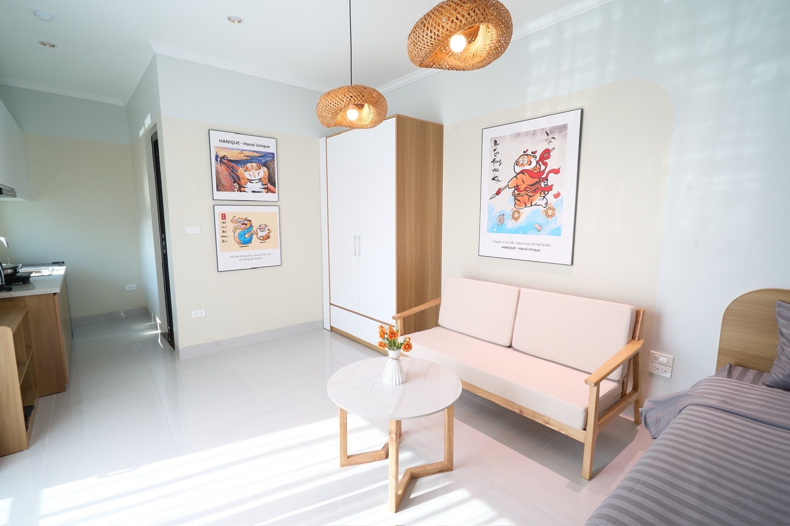 A modern room with a round white table, a wooden sofa, and two hanging wicker lamps.
