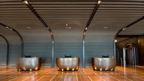 A modern reception area with three metallic reception desks and a patterned wooden floor. - Pan Pacific Dalian (Dalian)