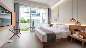 A modern bedroom with a large bed, a wooden bedside table, a wall-mounted TV, and a sliding glass door leading to a balcony. - TANG House (Wanning)