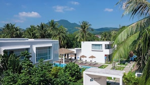 A resort with modern architecture, a pool area, and lush greenery. - TANG House (Wanning)