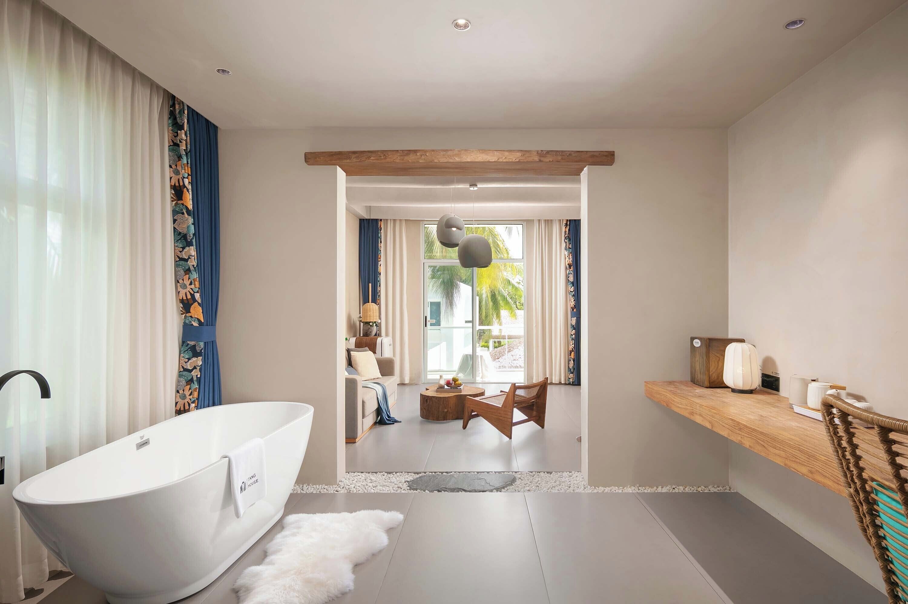 Een moderne badkamer met een vrijstaand bad, een houten wastafelmeubel en een groot raam met uitzicht op de natuur.