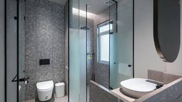 A modern bathroom with a glass-enclosed shower, a white toilet, and a large sink with a marble countertop.