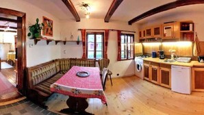 Una stanza accogliente con una panca di legno, un tavolo da pranzo con tovaglia a quadri, una lavatrice e un angolo cottura con mobili in legno.