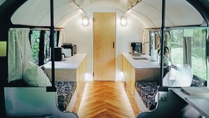 A compact RV interior with a kitchenette, a central door, and seating areas with windows. - 1 bedroom accommodation in Lavenham (Bury St Edmunds)