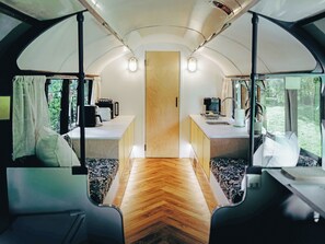 Ein kompaktes Wohnmobil-Interieur mit einer Küchenzeile, einer Mitteltür und Sitzbereichen mit Fenstern.