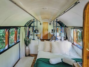 Ein gemütliches Zimmer mit einem Bett, einem kleinen Tisch, einem Stuhl und einem fenster mit Vorhängen.