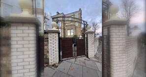A gated entrance to a brick house with a traditional design, a gated driveway, and a clear sky. - Serene 3BDR Garden Retreat by Hampstead Heath (Greater London)