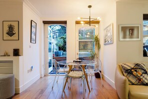 Un salon moderne avec une table à manger en verre, un canapé et une porte donnant sur un jardin.