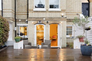 A brick building with a wooden deck and outdoor seating area. - Serene 3BDR Garden Retreat by Hampstead Heath (Greater London)