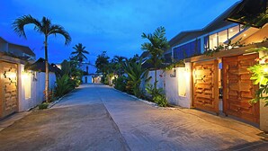 A well-lit pathway leading to a building with a wooden door and a sign that reads "USA". - Chez Judy Resort (Panglao)