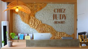 A reception desk at Chez Judy Resort with a decorative wall, a computer, and a plant. - Chez Judy Resort (Panglao)